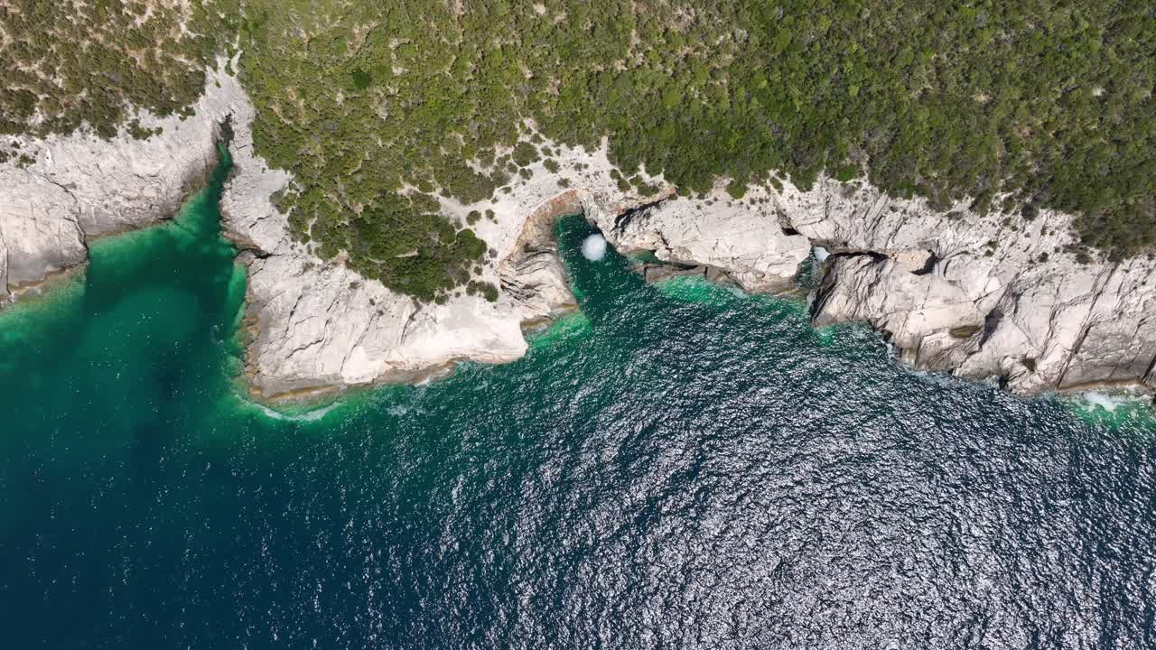 A stunning top-down drone shot of the rugged, rocky coastline of Dugi Otok, Croatia. The shot captures the contrast between the deep blue sea and the turquoise water