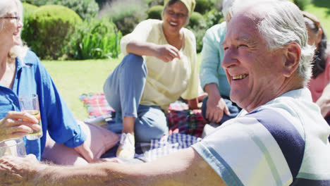 Glücklicher-älterer-Kaukasischer-Mann,-Der-Bei-Einem-Picknick-Mit-Verschiedenen-Freunden-Im-Sonnigen-Garten-Lacht,-Zeitlupe