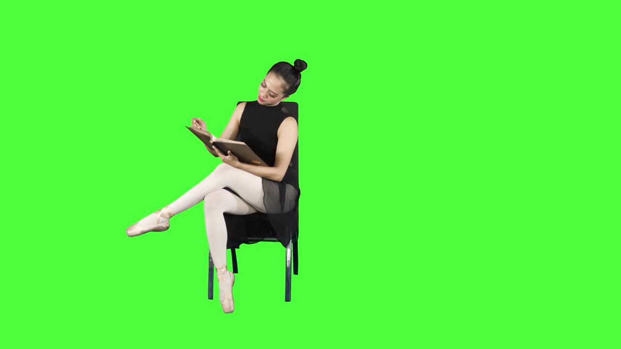 Ballet dancer sits on chair while reading a book