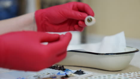 Synthetic eye in doctor's hands. Medical specialist in red latex gloves holding artificial eye prosthesis. Close-up. Ophthalmology concept.