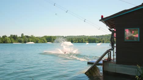 Ein-Mann,-Der-Durch-Ein-Kabel-Für-Einen-Wasserskilift-Gezogen-Wird,-Fällt-In-Das-Seewasser-Der-Freizeitinsel-Cergy-pontoise-In-Paris,-Frankreich