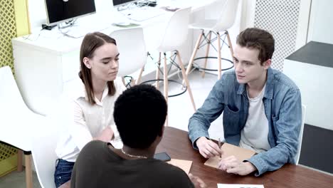 toma media de tres estudiantes universitarios haciendo una lluvia de ideas mientras hacen un proyecto juntos. grupo de jóvenes sentados en el escritorio y discutiendo ideas