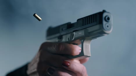 person with red fingernail polish firing gun and ejecting casing