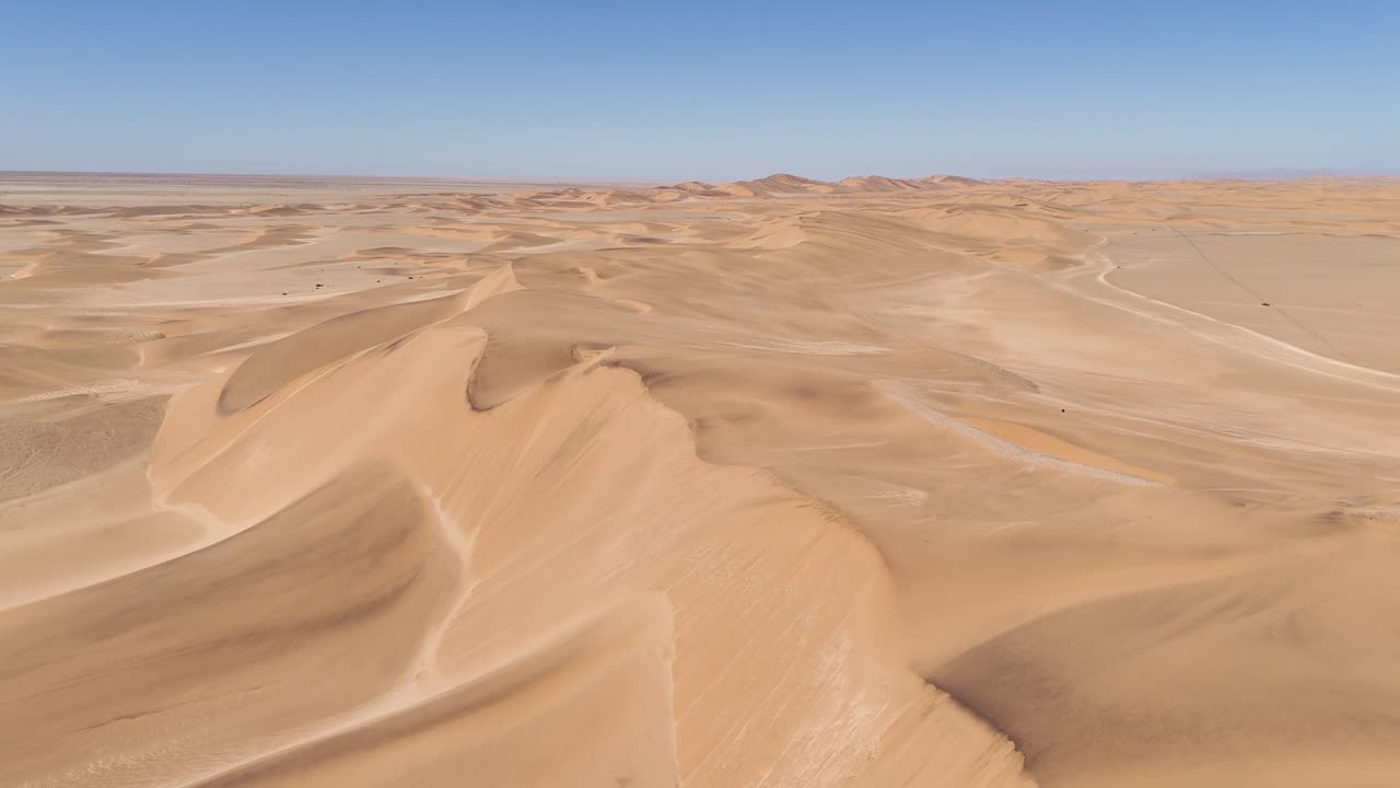 Aerial drone of the Namib Desert dunes near Swakopmund, Namibia, where golden sand meets the deep blue Atlantic Ocean