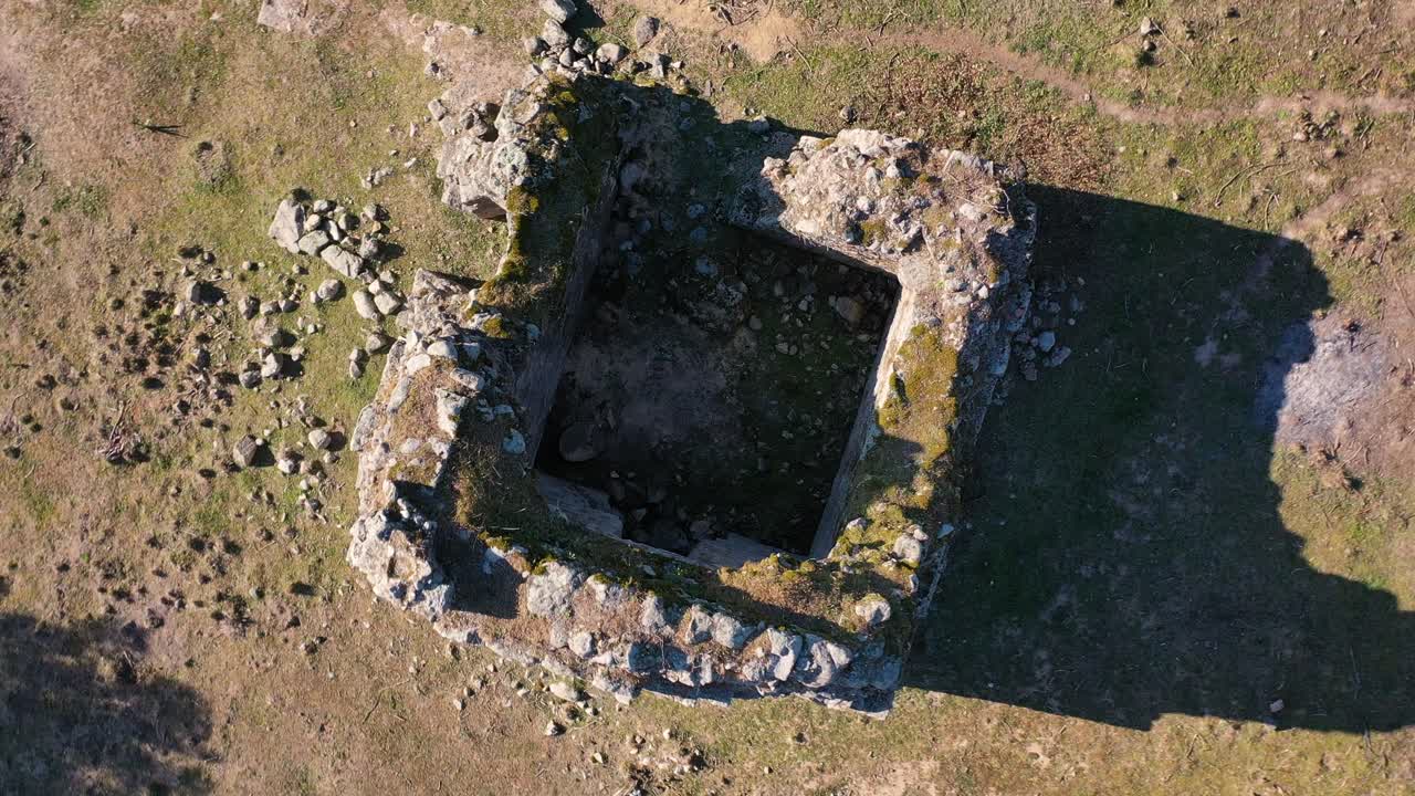 vuelo ascendente y orbital de drones a una ermita en ruinas medievales del siglo xi rodeado por restos de muros de piedra pastos robles junto a una carretera rural en el valle de tietar, ávila, españa