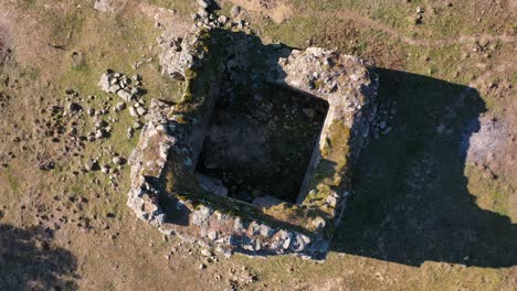 Ascending-and-orbital-drone-flight-to-a-hermitage-in-medieval-ruins-from-the-11th-century-surrounded-by-remains-of-stone-walls-pastures-oak-trees-next-to-a-rural-road-in-the-Tietar-Valley,-Avila-Spain