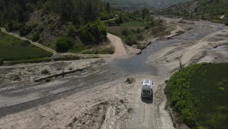 Drohnenaufnahme-Eines-Weißen-Lieferwagens,-Der-Am-Campingplatz-Am-Fluss-Vorbeifährt