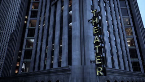 a tall theater building in a city at night