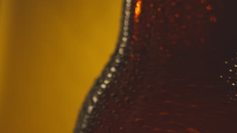 Macro-Shot-Of-Condensation-Droplets-On-Revolving-Bottle-Of-Cold-Beer-Or-Soft-Drinks-Against-Yellow-Background-3