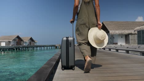 slow motion: young woman checking in at luxury hotel pulling small trolley luggage.