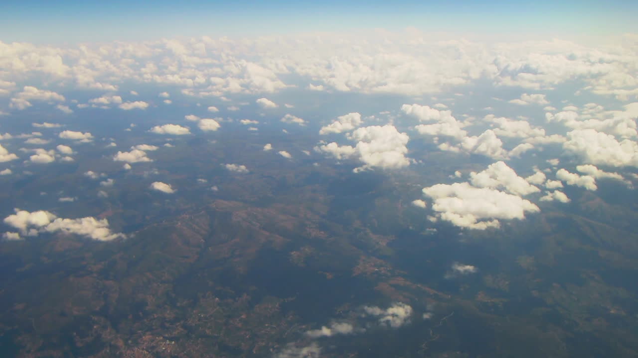 Aerial view of mountains and scattered clouds from airplane window