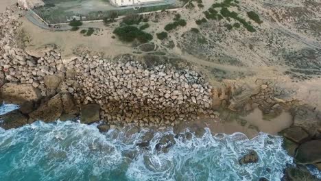 Aerial-birds-eye-view-looking-down-at-sea-with-Waves-crashing-the-rocky-beach-at-Cadiz-in-Spain