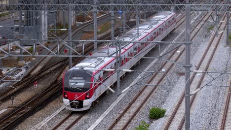 red and white colored train slowly running and crossing on a railway switch moving forward away from the station