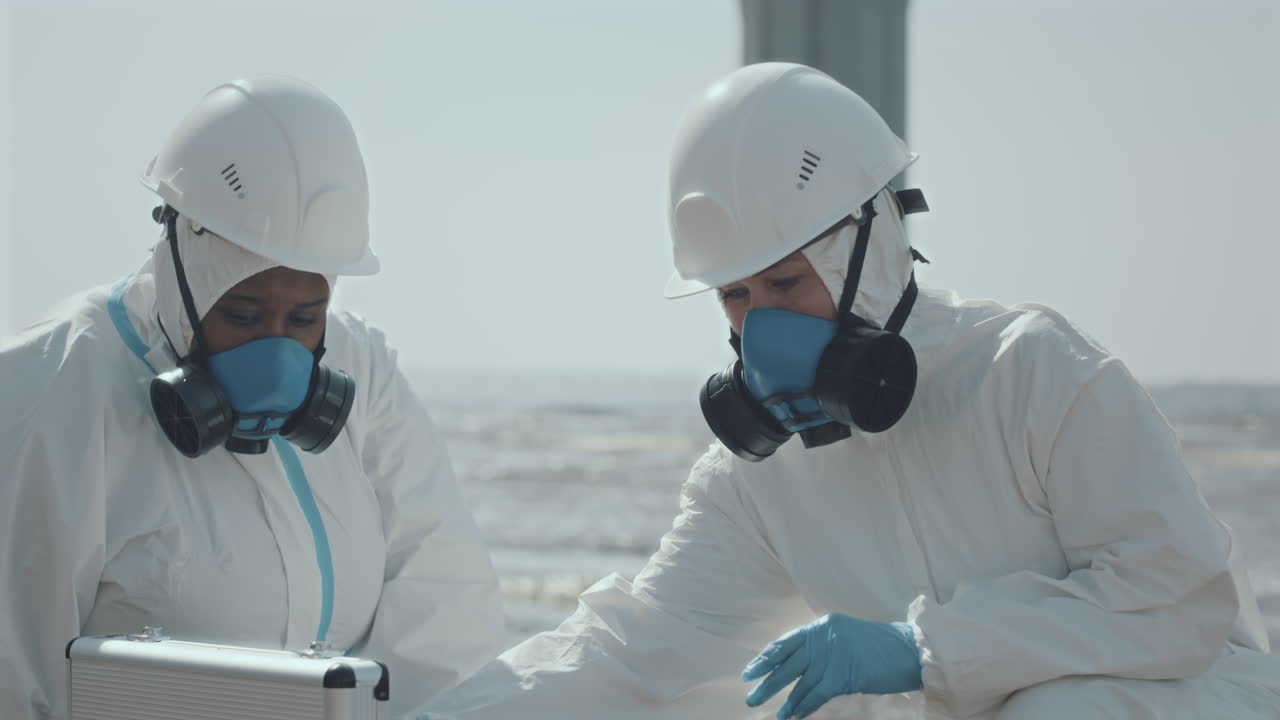 Two Ecologists in Coveralls Working with Samples of Polluted Water