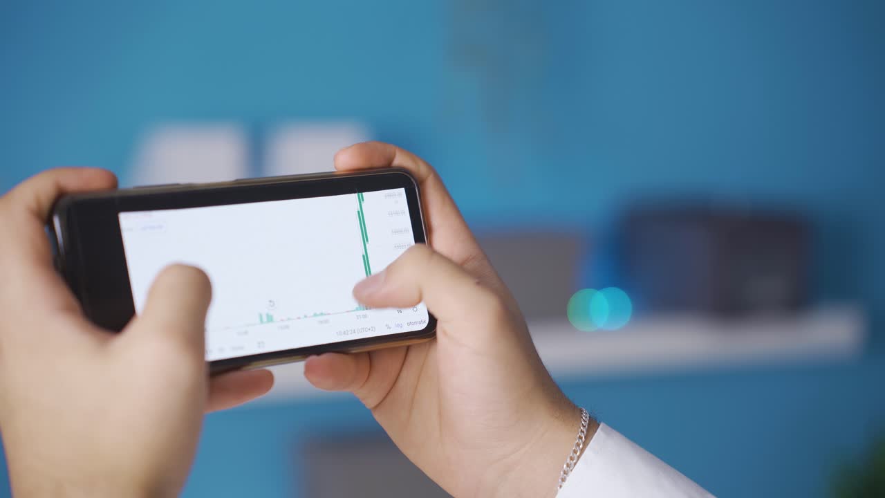 el comerciante que trabaja con un teléfono inteligente se alegra de ganar en el comercio en línea del mercado de valores.