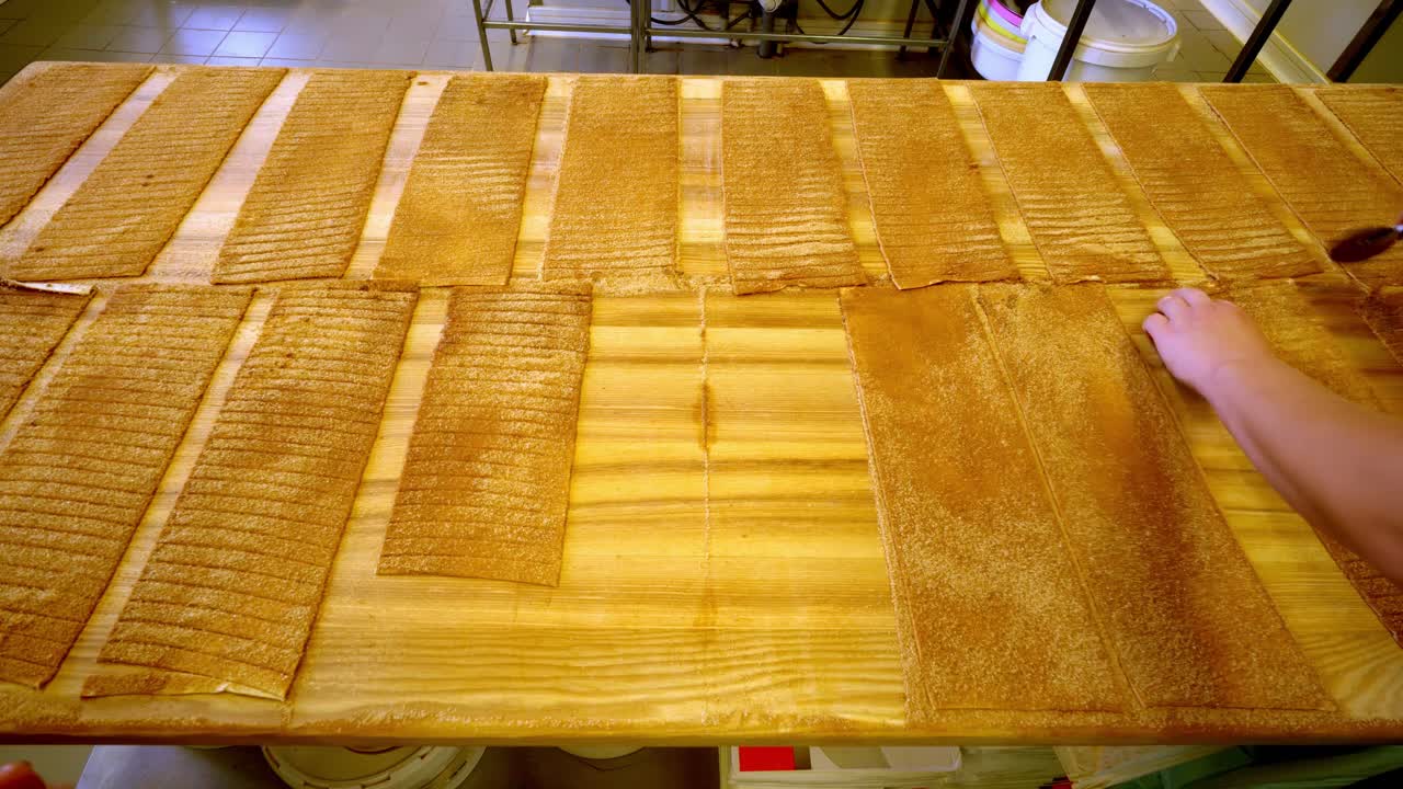 Hand arranges seaweed sheets on wooden table for culinary preparation