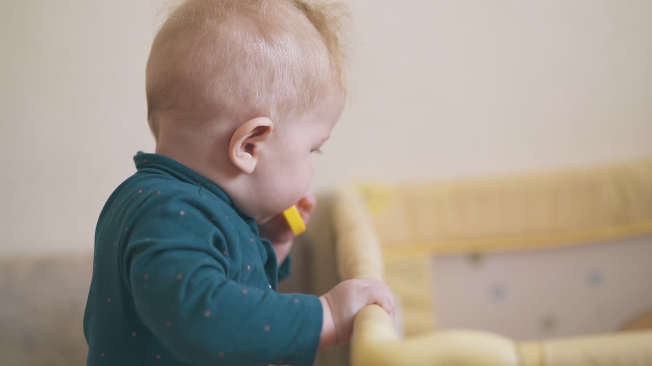 cute kid leans on playpen and sister throws out toys in room