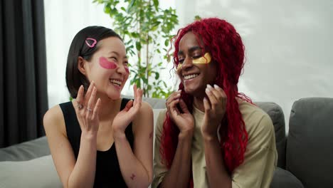 dos jóvenes hermosas mujeres multiétnicas con parches debajo de sus ojos en casa