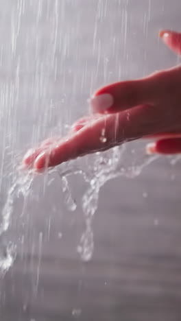 woman holds palms under shower sprays in bathroom closeup. lady enjoys pure liquid drops falling down in washroom. body hygiene and fun at home