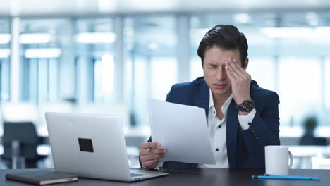 stressed and tensed indian manager reading and signing reports