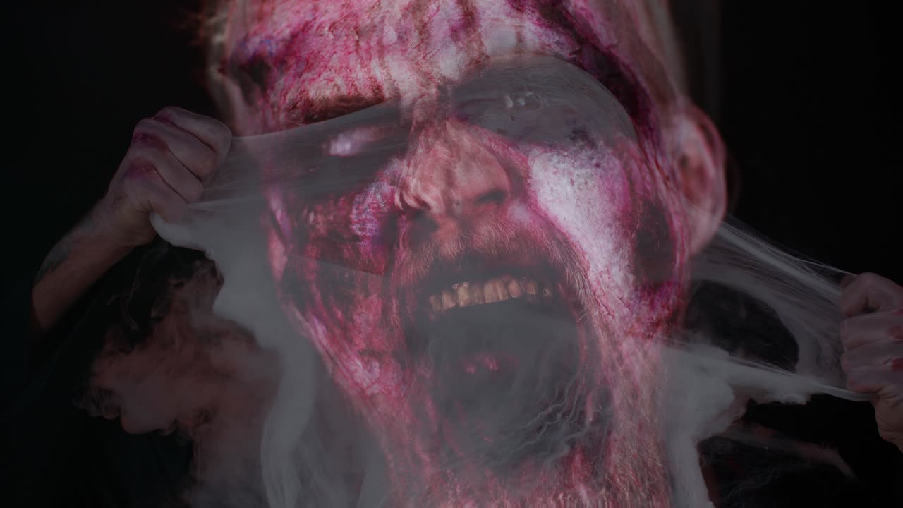 Scary wounded zombie undead guy making faces, hiding through spider web, smiles terribly, scares