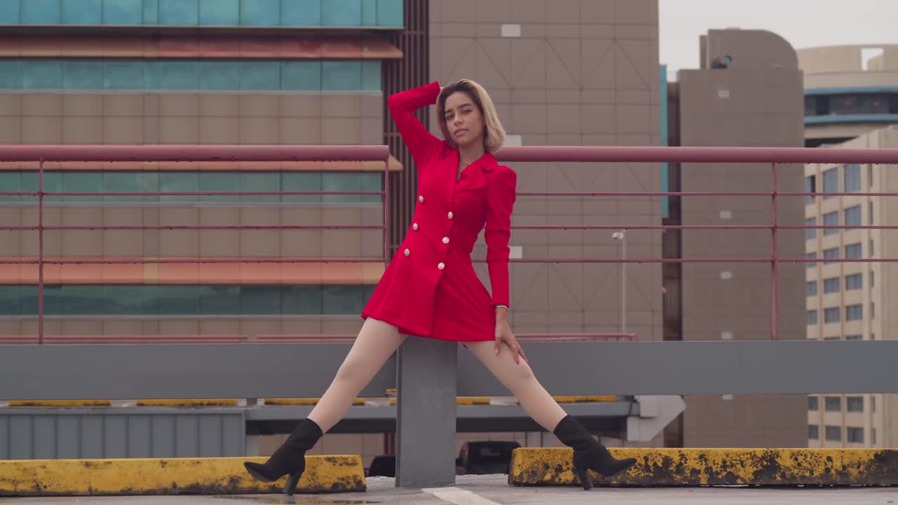 트리니다드 주 포트 오브 스페인에서, 히스패닉 뿌리를 가진 어린 소녀는 빨간 드레스를 입고 지붕 위에 서 있습니다.