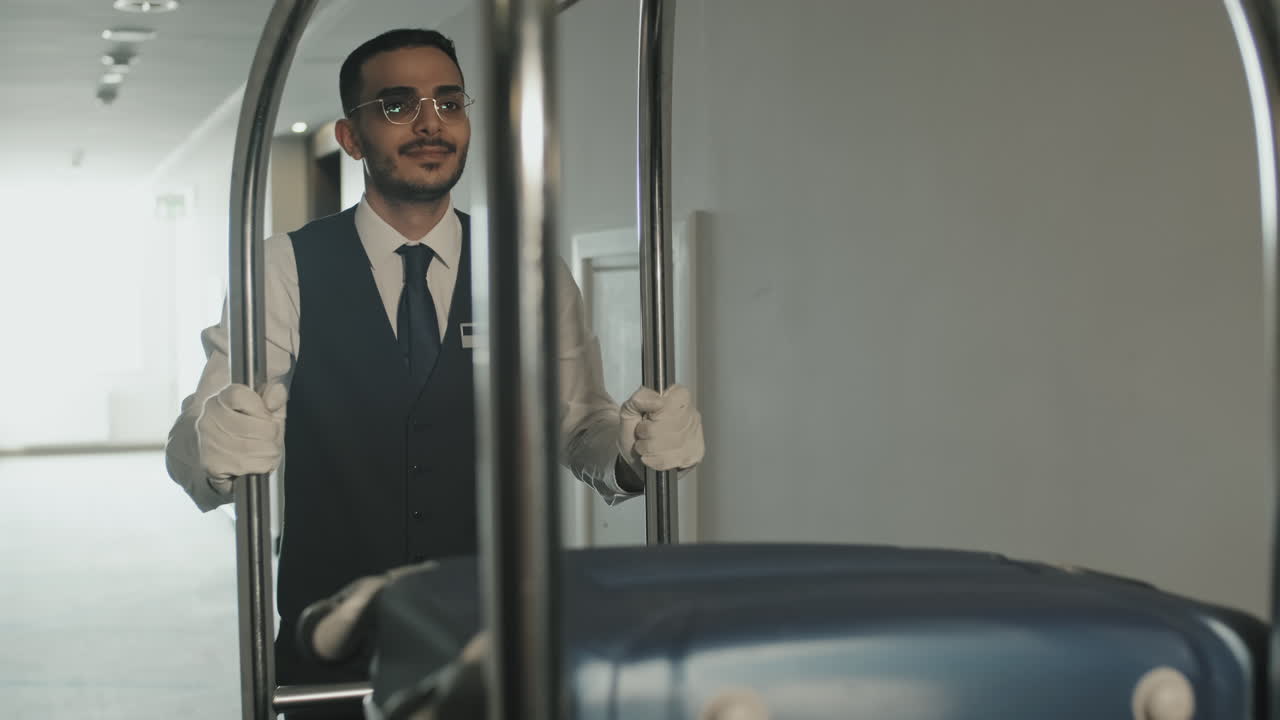 Fattorino con carrello portabagagli che cammina lungo il corridoio di un hotel