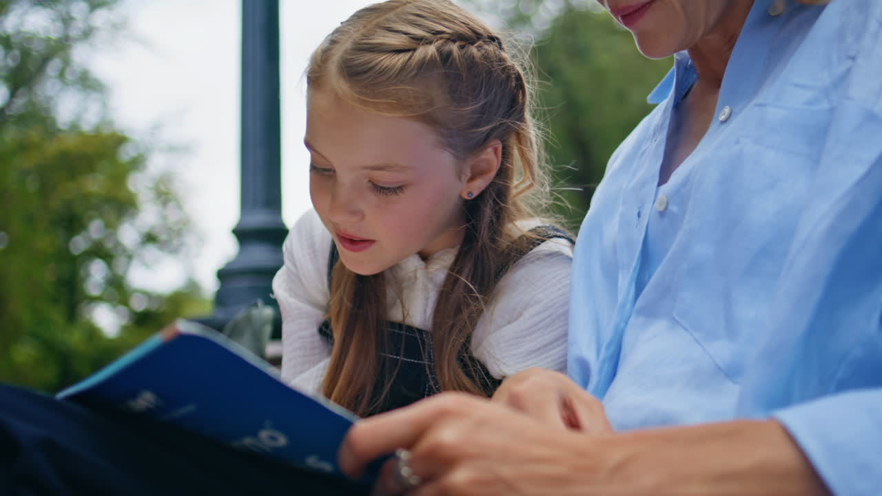 Closeup schoolgirl talking mom at park. Cute small kid writing copybook studying