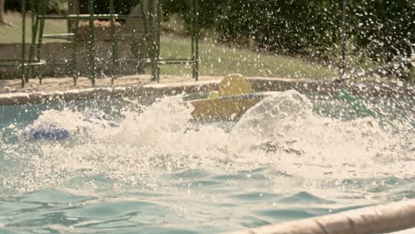 caucasian child diving face down a slide into the pool in slow motion