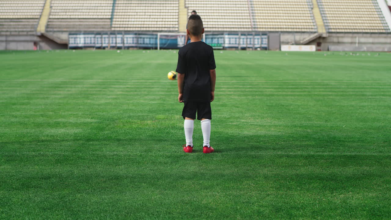 Young boy practicing soccer with a coach at a stadium
