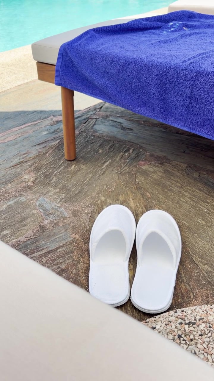 Hotelsko ved en liggestol på pooldækket, der nyder en afslappende ferie på et spa-resort. Turist slapper af udendørs på en solrig sommerdag. Vertikal video i POV-stil til sociale medier (UGC).
