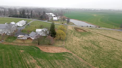 Eine-Luftaufnahme-Des-Düsteren-Ackerlandes-In-Pennsylvania-Mit-Vorbeifahrenden-Lastwagen,-Die-Waren-Liefern