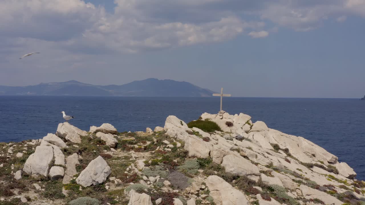 Seagulls on an uninhabited island in Greece - Orthodox cross in the background