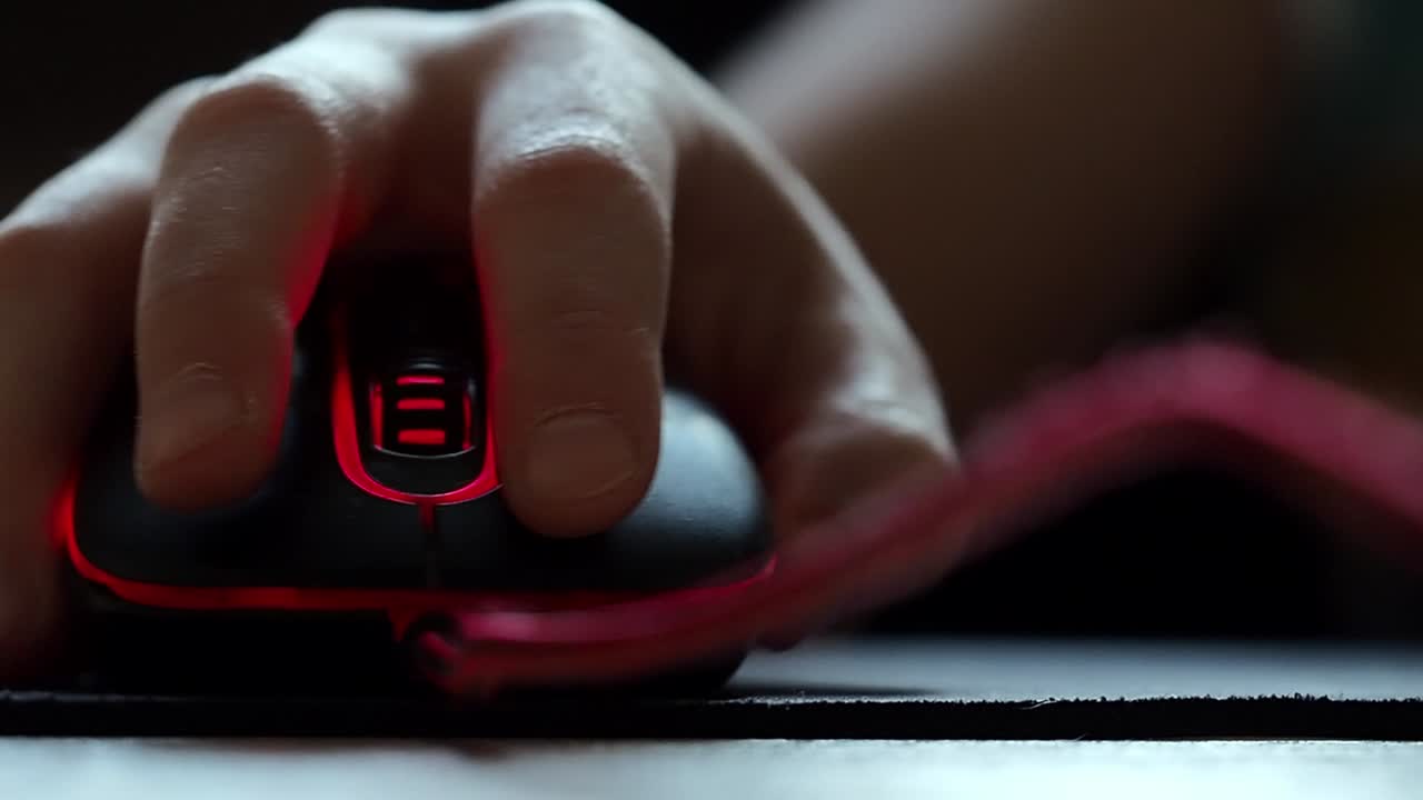 la mano de un adolescente con un ratón de computadora en primer plano.