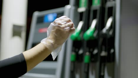 Person-wearing-safety-disposable-glove-before-refueling-car-on-a-gas-station