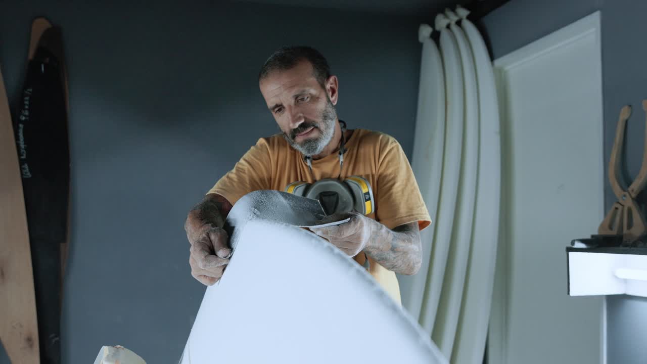 hombre enfocado usando papel de lija en la tabla de surf