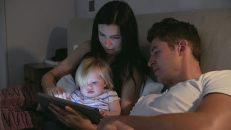 Familie-Sitzt-Im-Bett-Und-Schaut-Auf-Ein-Digitales-Tablet