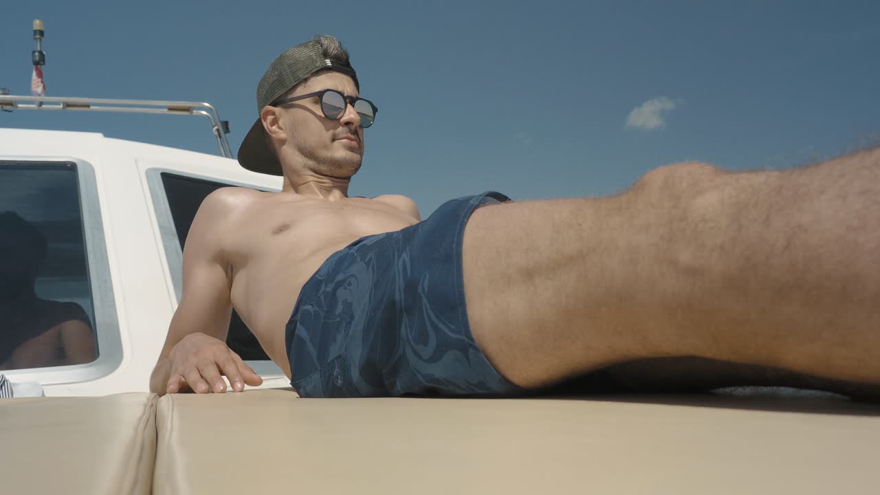 hombre joven, atlético, guapo, milenario relajándose en un viaje en barco