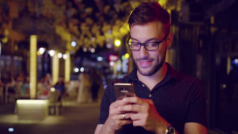 hombre usa teléfono inteligente por la noche en la ciudad
