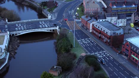 Vista-Aérea-Mirando-Hacia-El-Centro-De-La-Ciudad-Canal-Rotonda-Infraestructura-Calles-Suburbanas-Tráfico-Al-Amanecer-Lento-Aumento