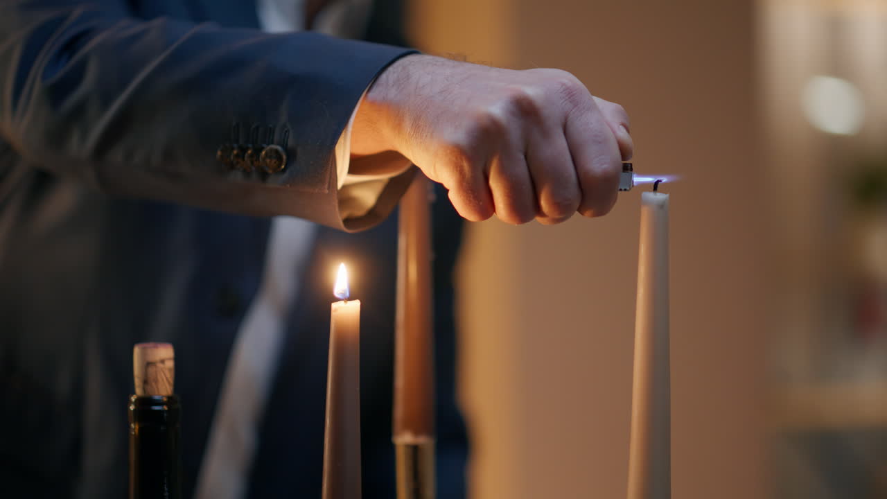 Primo piano di un uomo che si sistema gli occhiali durante una serata d'anniversario. Il signore accende le candele.
