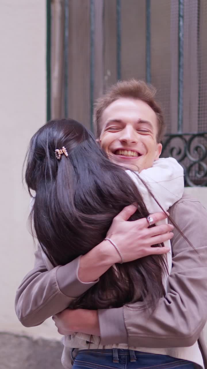 Giovane uomo felice che abbraccia una donna all'aperto