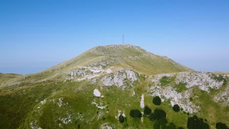 aerial approaching tall telecommunications antenna on the peak of a tall mountain