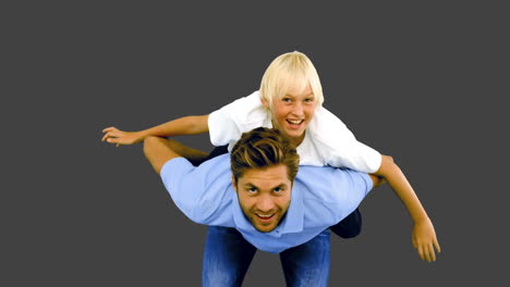 Son-having-a-piggy-back-on-his-father-on-grey-background