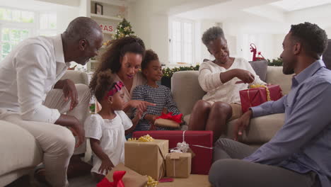 multi-generation family celebrating christmas at home opening presents together