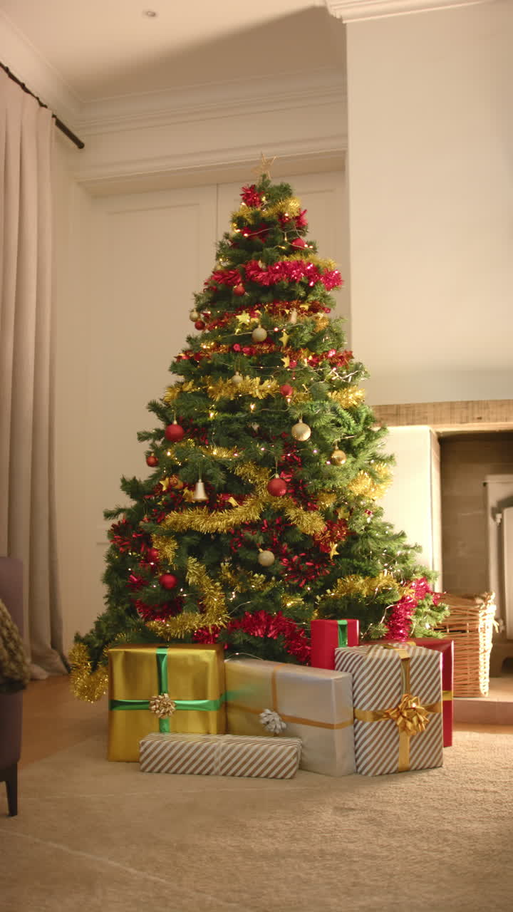 Vertical video of presents under decorated christmas tree in living room, slow motion