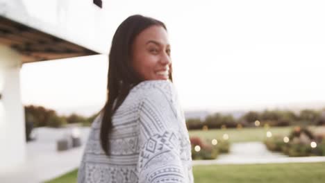 Portrait-of-biracial-woman-holding-hand-of-partner,-beckoning-and-smiling-in-garden-in-slow-motion