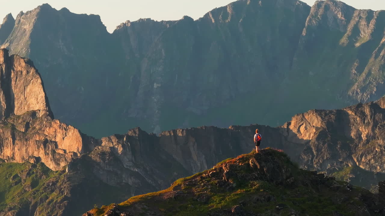 Drone orbit hiker on arctic Norway mountain top with majestic sunset view