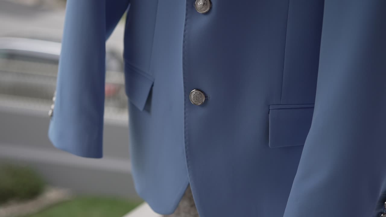 Detailed close up of blue wedding suit with metallic buttons and fine stitching