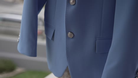 detailed close up of blue wedding suit with metallic buttons and fine stitching
